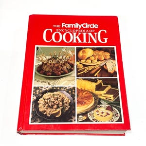 May include: A red hardcover cookbook titled "The Family Circle Encyclopedia of Cooking". The cover features four photos of different dishes: a roasted meat dish, a bread and pastry dish, a pasta dish, and a dessert dish.