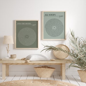 K&ouml;nnte beinhalten: Zwei gerahmte Kunstdrucke mit Songtexten in einem kreisf&ouml;rmigen Design. Die Drucke haben einen salbeigr&uuml;nen Hintergrund und sind in hellen Holzrahmen. Einer der Drucke lautet "Into the Mystic", der andere "All Your'n". Sie werden auf einer hellen Holzbank ausgestellt.