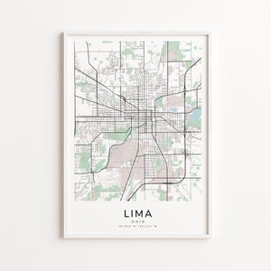 May include: A framed map print of Lima, Ohio, featuring a detailed street layout in black lines against a light background with green and pink areas. The city name and coordinates are printed at the bottom.