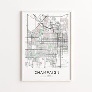 May include: A framed map print of Champaign, Illinois, featuring a detailed street grid and surrounding areas. The map is in black and white with subtle color accents, and the city name is displayed in a clean font at the bottom.