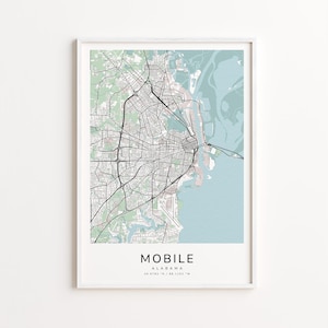 May include: A framed map print of Mobile, Alabama, featuring a detailed black and white street grid against a backdrop of light green and blue hues. The city's name is printed in a bold, modern font at the bottom.