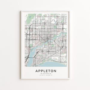 May include: A framed map print of Appleton, Wisconsin, featuring a detailed street layout in black lines against a light pink and green background. The city name is centered at the bottom, with coordinates below.