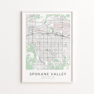 May include: A framed map print of Spokane Valley, Washington, with a white border. The map features black street lines, green shaded areas, and a pinkish-beige area. The text "Spokane Valley" and coordinates are printed at the bottom.