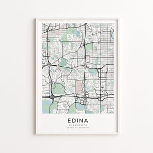May include: A framed map print of Edina, Minnesota, featuring a detailed black and white street grid with green and pink shaded areas. The city name and coordinates are printed at the bottom.