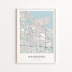 May include: A framed map print of Hammond, Indiana, featuring a detailed street layout in black lines against a light background. The map includes the city's name and coordinates at the bottom. The top portion shows a light blue body of water.