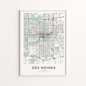 May include: Framed map print of Des Moines, Iowa, featuring a detailed black and white road network over a light background. The city name is centered at the bottom, with the state and coordinates below.
