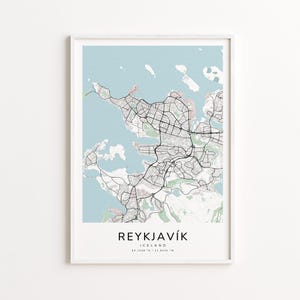 May include: A framed print of a map of Reykjavík, Iceland, set against a light blue backdrop. The map shows black road networks and white land areas. The city name and country are printed in black at the bottom, along with the coordinates.