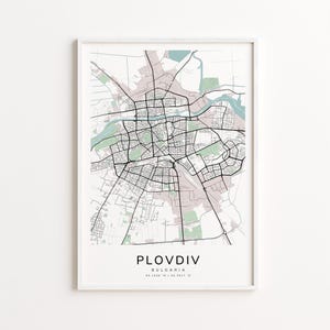 May include: A framed map print of Plovdiv, Bulgaria, featuring a detailed street layout in black lines against a neutral background with green and pink accents. The city name is centered at the bottom, with coordinates below.