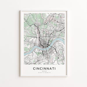 May include: Framed map print of Cincinnati, Ohio, featuring a detailed street layout with a river running through the city. The map includes green areas and is labeled "Cincinnati" in a clean, modern font.