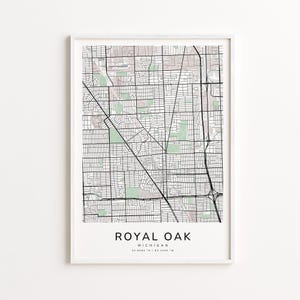 May include: A framed map print of Royal Oak, Michigan, featuring a detailed street grid in black lines against a light background with green and pink areas. The city name and coordinates are printed at the bottom.