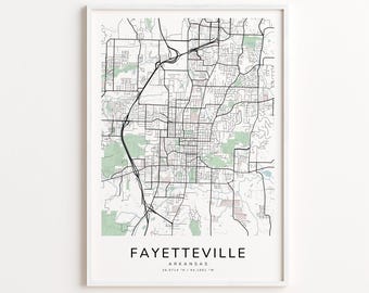 Op de afbeelding: Een ingelijste kaartprint van Fayetteville, Arkansas, met een gedetailleerde stratenkaart in zwarte lijnen op een witte achtergrond. Groene gebieden stellen parken voor. De stadsnaam en coördinaten staan onderaan afgedrukt.