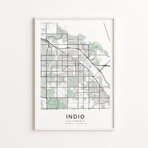 May include: A framed map print of Indio, California, featuring a detailed street grid, parks, and waterways. The map is in black and white with green accents, and the city name is displayed in bold text at the bottom.