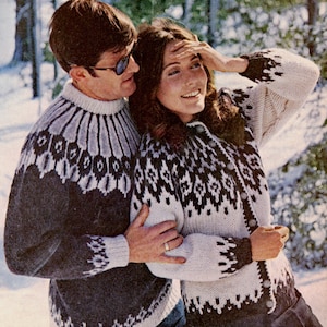 May include: A couple wearing matching patterned sweaters in a snowy outdoor setting. The sweaters feature a white, black, and gray geometric design. The man wears a dark gray sweater, while the woman wears a cardigan with the same pattern.