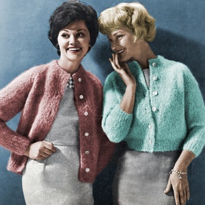 May include: Two women wearing cardigans. The woman on the left is wearing a pink cardigan and the woman on the right is wearing a light blue cardigan.