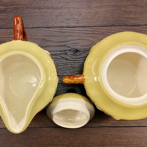Op de afbeelding: Een set van drie gele keramische theekopjes met bruine handvatten. De kopjes zijn versierd met een bruin en geel patroon.
