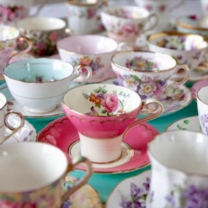 May include: A collection of vintage teacups and saucers in various floral patterns and colors, including pink, blue, and white.
