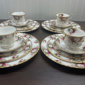 May include: Four sets of fine bone china teacups and saucers with a floral pattern. Each set includes a teacup, saucer, and a larger plate. The cups and saucers have a gold trim.