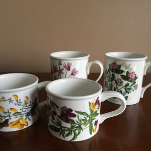 May include: Four white ceramic mugs with floral designs. Each mug features a different flower and has a handle.