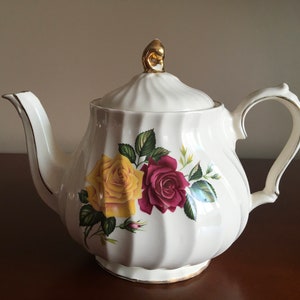 Peut inclure: Théière blanche avec une bordure dorée et un motif floral représentant des roses rouges, jaunes et vertes.