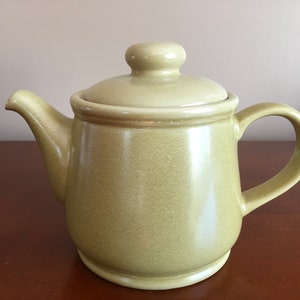 May include: A green ceramic teapot with a lid and a handle. The teapot has a speckled finish.