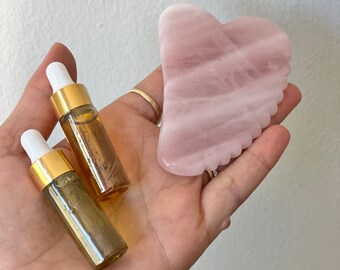 May include: Two small amber glass bottles with gold caps and droppers, and a pink rose quartz gua sha tool.