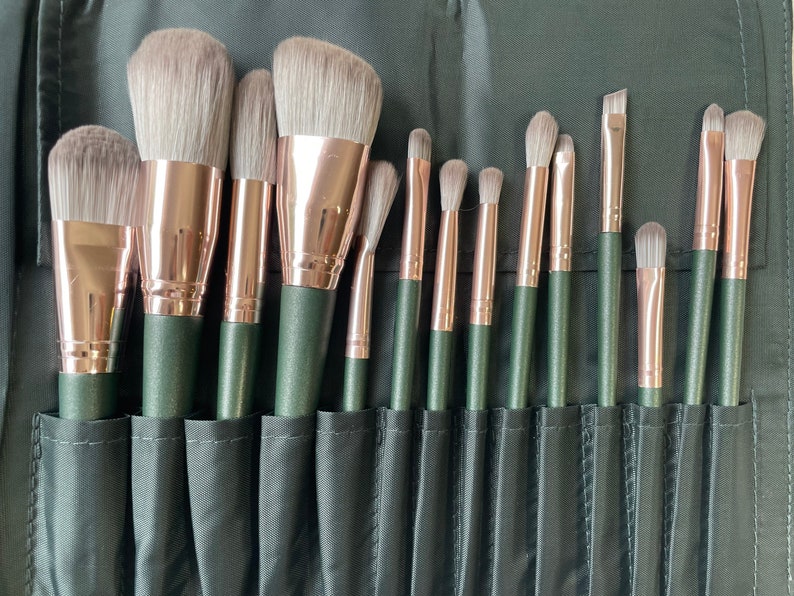 Pu&ograve; includere: Un set di 15 pennelli da trucco con ferrule dorate rosa e manici neri. I pennelli sono disposti in un astuccio nero con slot individuali per ogni pennello.
