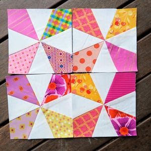 May include: Four patchwork quilt blocks arranged in a square. Each block has a white centre with radiating triangles of patterned fabric in pink, yellow, orange, and purple. Patterns include stripes, polka dots, and floral designs.