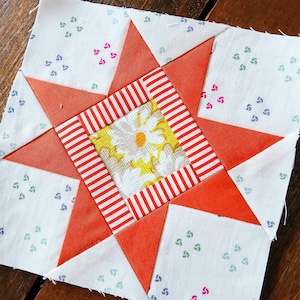 May include: A patchwork quilt block with a red and white striped square in the centre, surrounded by orange triangles and white squares with a green and pink swirl pattern.
