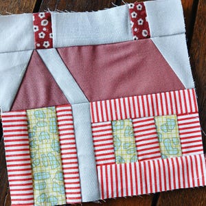 May include: A patchwork quilt block featuring a red, white and blue colour scheme. The block is composed of various geometric shapes and patterns, including stripes, polka dots and a chequered pattern.