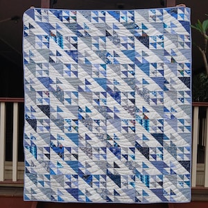 May include: A blue and white quilt with a geometric pattern of triangles. The quilt is quilted with a wavy pattern.