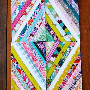 Puede incluir: Cuatro cuadrados de tela coloridos cosidos juntos para crear un patrón de diamante. Cada cuadrado está hecho de múltiples tiras de tela en varios colores y patrones, incluyendo rosa, amarillo, verde, azul y blanco.