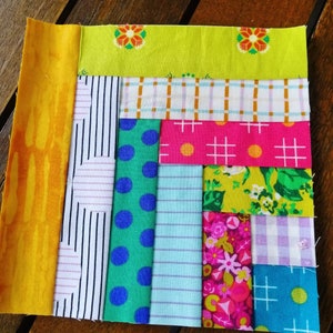 May include: A patchwork quilt block with a variety of colorful fabrics, including yellow, green, blue, pink, and white. The block is made up of strips of fabric sewn together in a diagonal pattern.