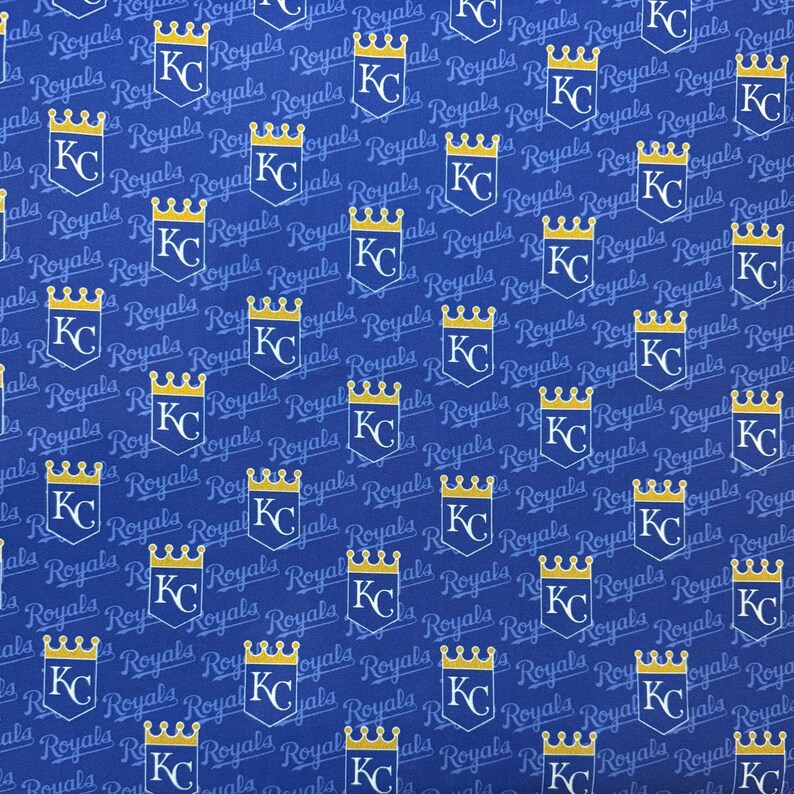 May include: Blue fabric with a repeating pattern of the Kansas City Royals logo. The logo features a gold crown above the letters "KC" inside a white shield. The word "Royals" is also printed on the fabric.