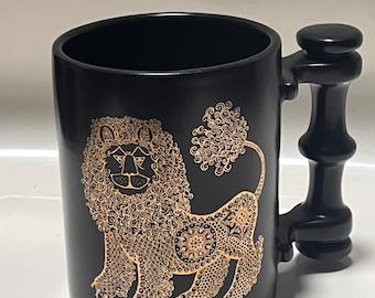 Pode incluir: Caneca de cerâmica preta com um design de leão dourado. A caneca tem uma alça de bambu preto.