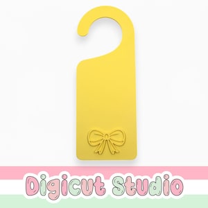 May include: A yellow door hanger with a bow design at the bottom. The hanger has a curved top for easy hanging. The words "Digicut Studio" are at the bottom of the image.