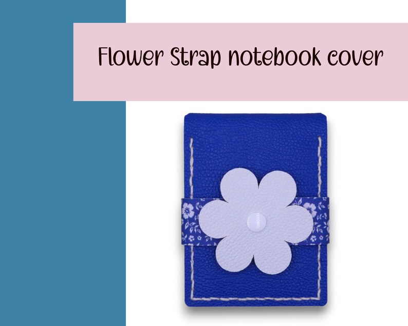 May include: A blue notebook cover with a white flower strap. The cover has white stitching and a floral patterned strap. The text "Flower Strap notebook cover" is displayed above the notebook.