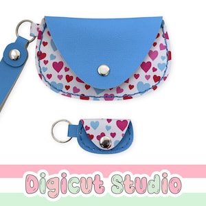Può includere: Una custodia blu e una custodia portachiavi più piccola abbinata, entrambe con sfondo bianco e un motivo di cuori rossi, rosa e azzurri. Ogni articolo ha una patta blu, una chiusura a scatto in metallo argentato e un anello argentato.