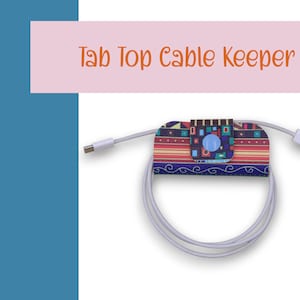 May include: A colorful cable keeper with a geometric pattern and a blue button. The keeper is attached to a white cable.