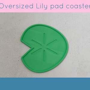 May include: A green, oversized lily pad coaster. The coaster is shaped like a lily pad with a section cut out. The text "Oversized Lily pad coaster" is at the top of the image.