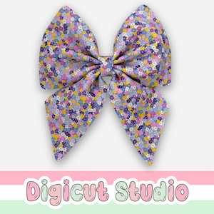 May include: A large fabric hair bow featuring a floral pattern in blue, purple, yellow, and pink. The bow is centrally positioned with a symmetrical design. The text "Digicut Studio" is at the bottom.
