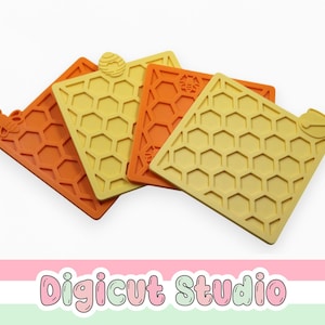 May include: Four square, honeycomb-patterned coasters in shades of yellow and orange. Each coaster has a unique bee or honeycomb design. The coasters are made of a flexible material and are arranged on a white background.
