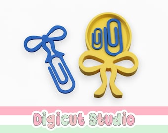 May include: Two decorative paper clips. One is a blue bow-shaped clip. The other is a yellow bow-shaped clip holding two blue paper clips. The image includes the text "Digicut Studio" in a pastel font.