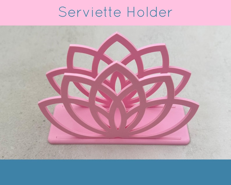 May include: A pink serviette holder with a lotus flower design. The holder is made of a solid material and has a rectangular base. The text "Serviette Holder" is displayed above the holder.