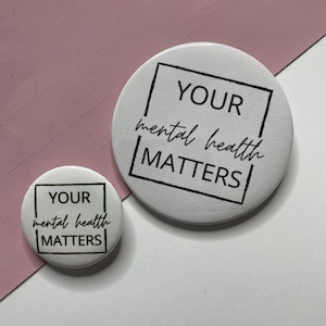 May include: Two white round buttons with black text. The larger button says "YOUR mental health MATTERS" in a black square. The smaller button says "YOUR mental health MATTERS" in a black square.