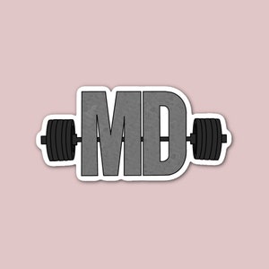 May include: A gray sticker with the letters "MD" in a bold, textured font. The letters are centered on a barbell with black weight plates on each end.