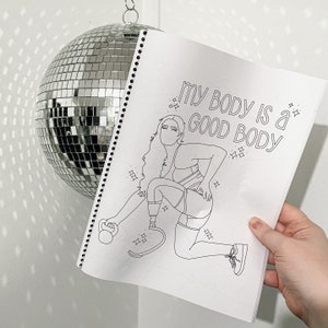 Op de afbeelding: Een zwart-witte kleurplaat met een vrouw die oefent met een gewicht. De tekst op de pagina luidt "My body is a good body."