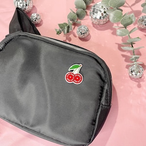 May include: Black zippered pouch with a red cherry pin that says "Eat Me" on it.
