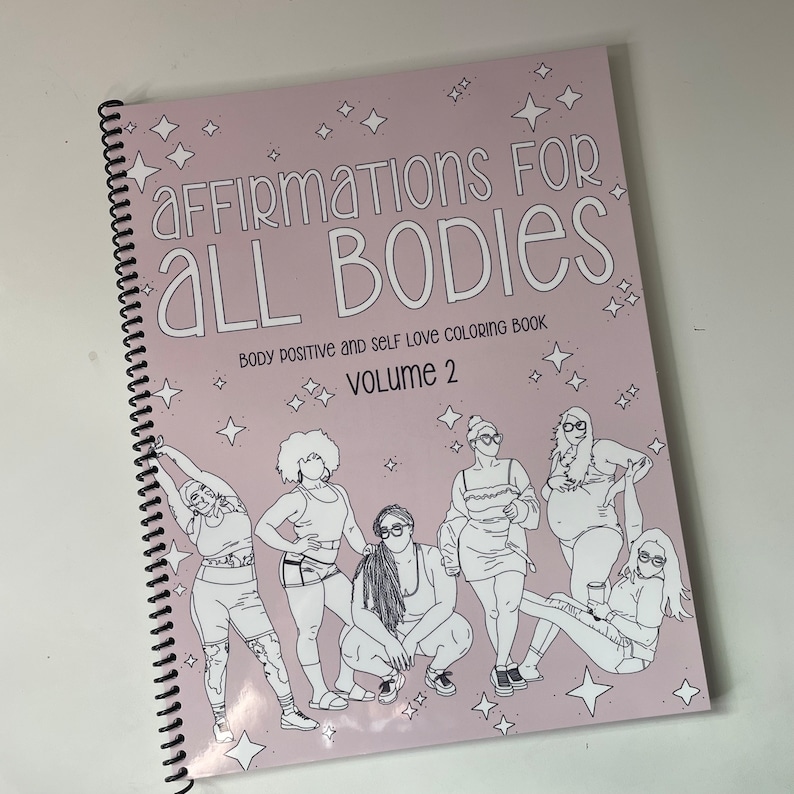 Op de afbeelding: Een roze kleurboek met de titel "Affirmations for All Bodies: Body Positive and Self Love Coloring Book, Volume 2". De omslag toont illustraties van zeven vrouwen in verschillende poses.