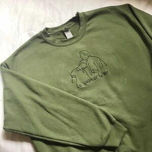 Puede incluir: Una sudadera verde con un dise&ntilde;o bordado en negro de dos figuras y el texto "to speak or to die".