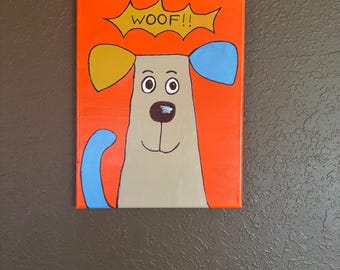 May include: A rectangular canvas painting featuring a cartoon dog with tan fur, blue and yellow ears, and a blue tail. The dog has big eyes and a black nose. A yellow speech bubble above the dog reads "WOOF!!". The background is orange.